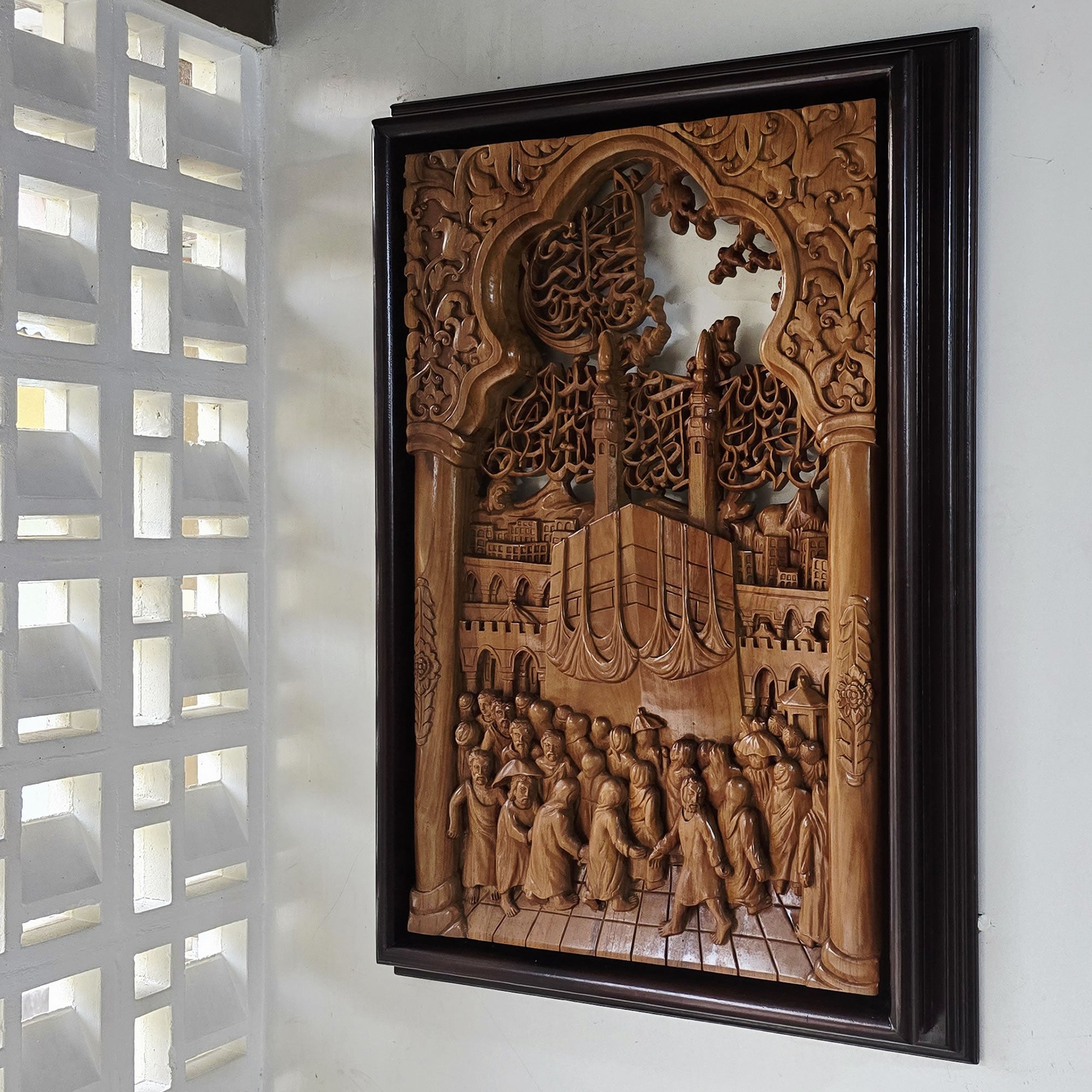 A large, intricately carved wooden wall art piece depicting Islamic Muslim Hajj Kaaba Teakwood Hand-Carved Sculpture Wall Art Interior Display