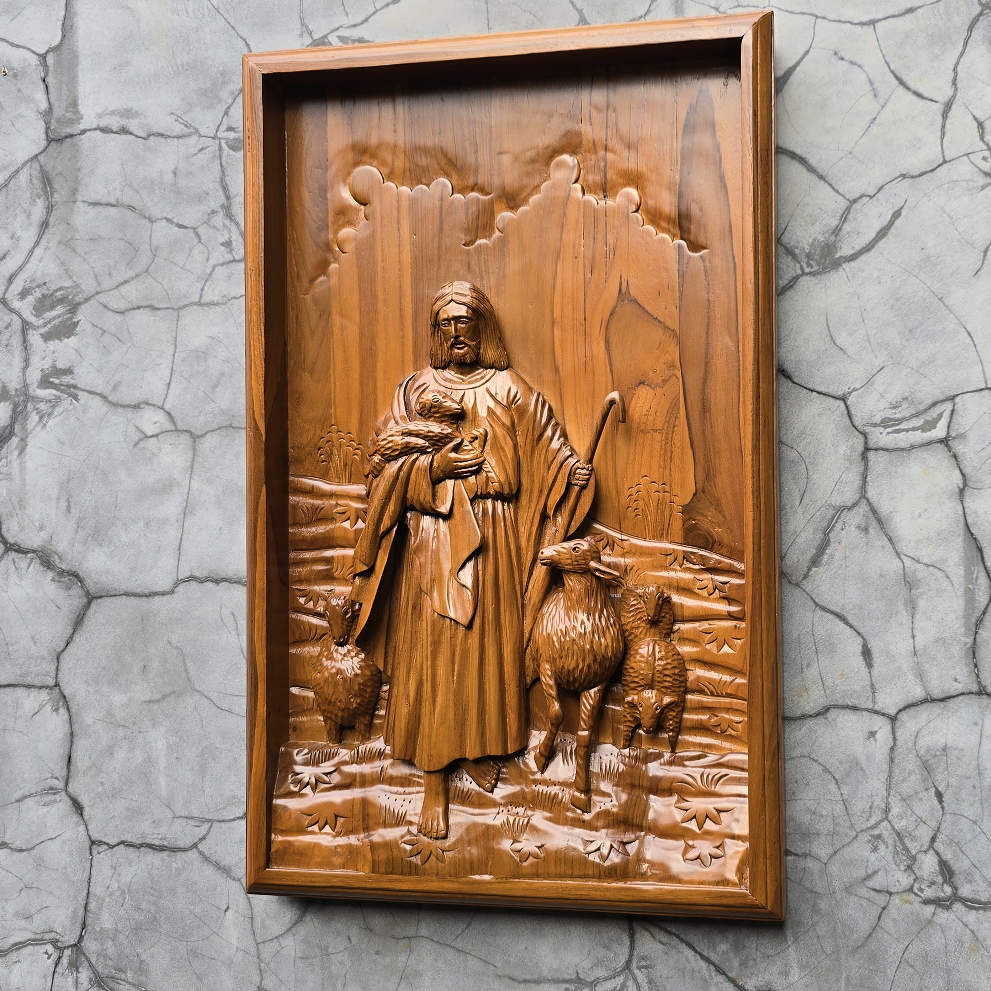 Wooden relief sculpture of a shepherd with two sheep on a textured wall.