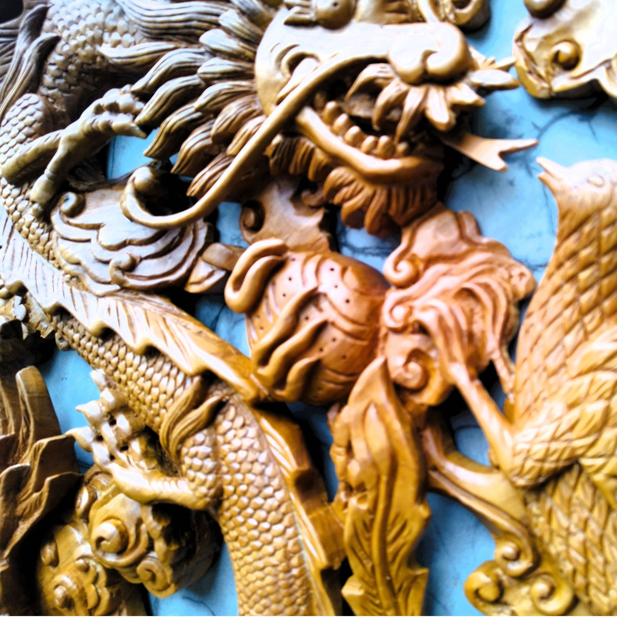 Close-up of the Phoenix bird detailing on the teakwood sculpture, highlighting the intricate hand-carved feathers and wood grain