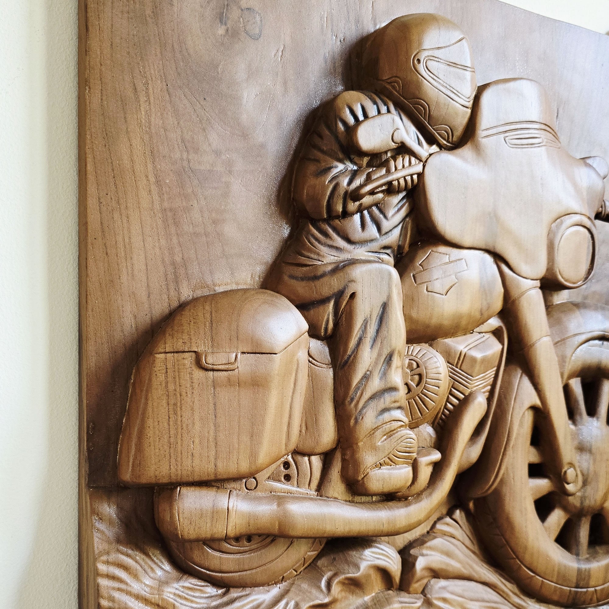 Close-up of the intricately chiseled engine details and exhaust pipes on the wooden motorcycle sculpture