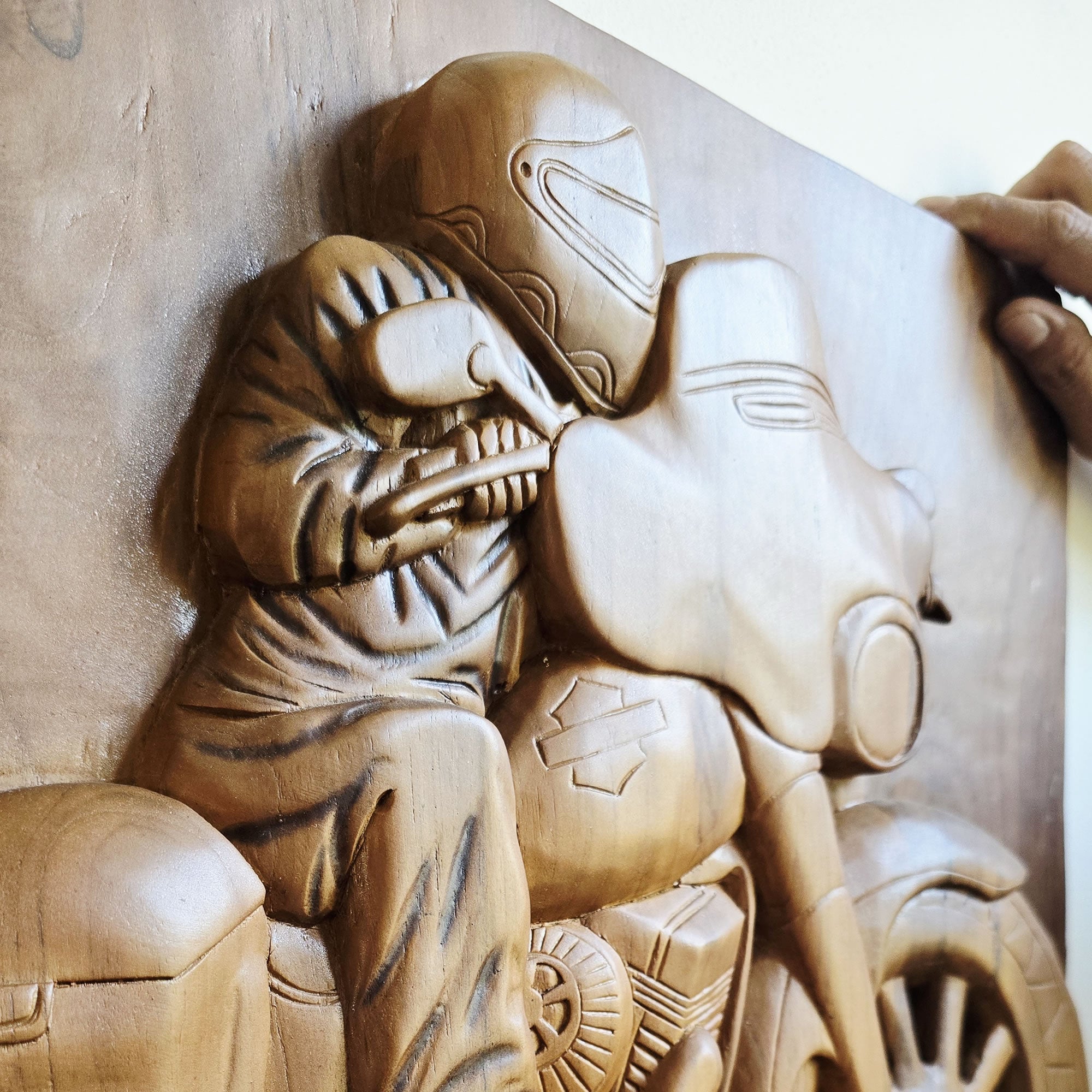 Close-up of the intricately chiseled engine details and exhaust pipes on the wooden motorcycle sculpture