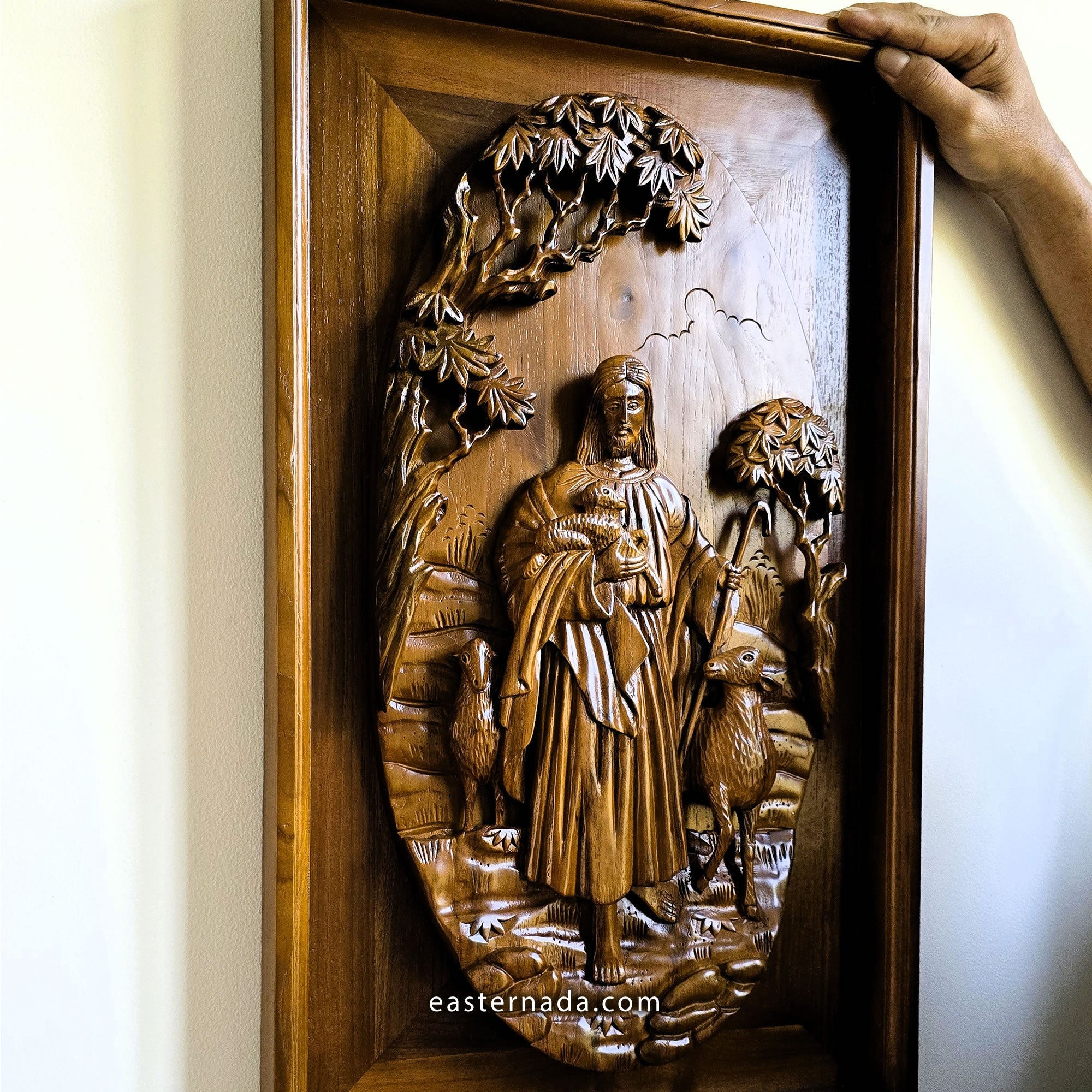 Detailed closeup of solid teak wood carving showing dimensional relief details of Jesus Christ as the sacred shepherd, hand-crafted wall sculpture.