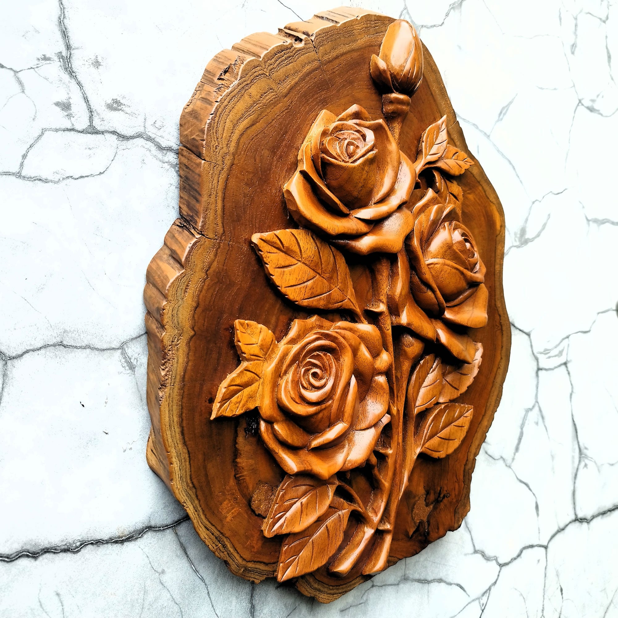 Side view of hand-carved teakwood roses sculpture highlighting the 3D relief carving and the thickness of the solid wood on a gallery wall