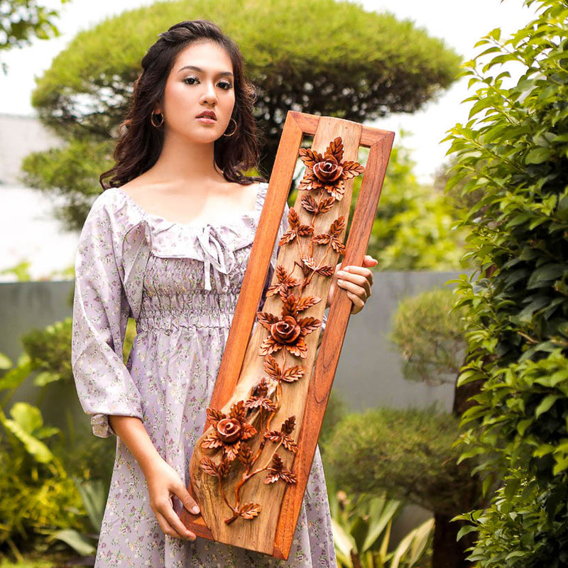 Professional model holding the 1-meter Eternal Blossom sculpture; showcasing the scale of the vertical teakwood and driftwood wall art.