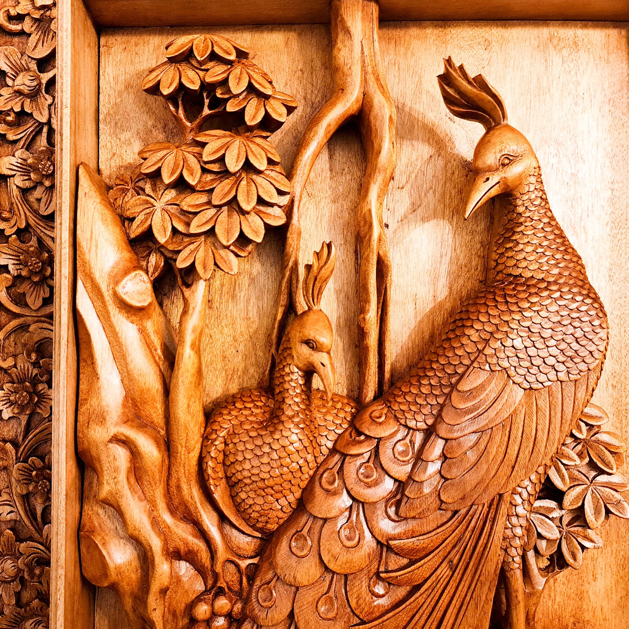Detailed hand-chiseled peacock feather textures in premium solid teakwood, showing the depth and precision of high-relief wood carving.
