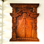 Frontal view of a hand-carved solid teakwood Gebyok wall art with doors closed, showing intricate Javanese floral carvings.