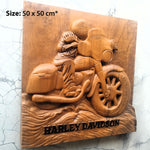 A rectangular wooden wall plaque featuring a carved Harley-Davidson motorcycle and rider, mounted against a light textured wall. The plaque has a size overlay reading 'Size: 50 x 50 cm*' in the top-left corner and the words 'HARLEY DAVIDSON' carved into the bottom edge.