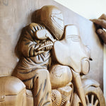 Close-up of the intricately chiseled engine details and exhaust pipes on the wooden motorcycle sculpture