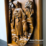 A close-up of a carved wooden relief plaque showing Jesus holding a lamb, mounted on a wooden backing. Text at the bottom right reads 'Jesus Shepard' and 'Stunning Relief Hand-Carving Solid Teakwood'.